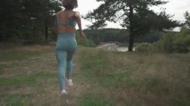 Ormanda yokuş yukarı koşan bir kadının yan görüntüsü.