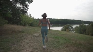 Ormanda yokuş yukarı koşan bir kadının yan görüntüsü.