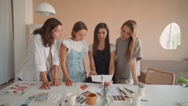 Vue de face de quatre belles femmes caucasiennes à l'atelier d'art. Un jeune professeur enseigne le dessin — Video