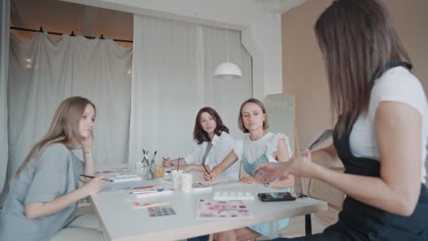 Vista frontal de cuatro hermosas mujeres caucásicas en el taller de arte. Un joven profesor enseña dibujo — Vídeo de stock