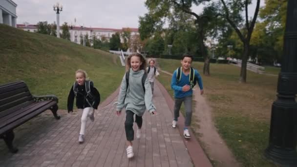Widok z przodu kaukaskie dzieci ze szkolnymi torbami biegającymi na szkolnym podwórku w szkole 4k. — Wideo stockowe
