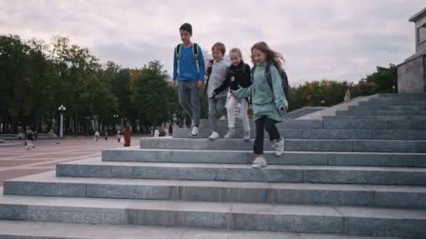 Happy schoolchildren run down stone stairs. Children are go from school — Stock Video