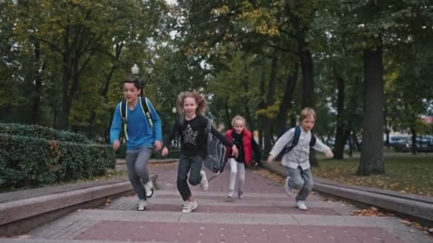 Skolbarn med ryggsäckar som springer uppför trappor nära skolan — Stockvideo