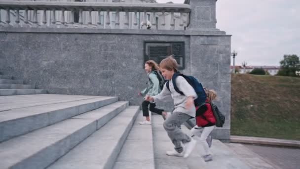 Colegiales con mochilas subiendo escaleras cerca de la escuela — Vídeos de Stock