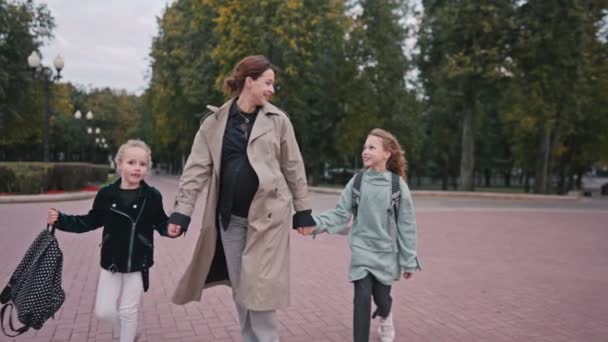 Mamma scorta le sue figlie a scuola. felice famiglia bambino sogno concetto di scuola. scolaretta corso di fretta per la lezione a scuola. bambino e mamma stile di vita addio prima di scuola — Video Stock