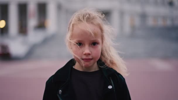 Ritratto di ragazza caucasica di 6 anni che guarda la macchina fotografica e sorride con sfondo urbano. Una ragazza con un dente da latte e 'caduta. Millennials, natura e felice concetto di gioventù — Video Stock