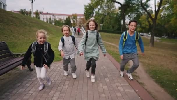 Μπροστά όψη των Καυκάσιων μαθητών με σχολικές τσάντες που τρέχουν στην αυλή του σχολείου στο σχολείο 4k. — Αρχείο Βίντεο