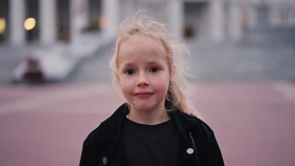 6 éves kaukázusi lány portréja, aki kamerába néz és városi háttérrel mosolyog. A tejfogú lány kiesett. Millennials, természet és boldog ifjúság koncepció — Stock videók