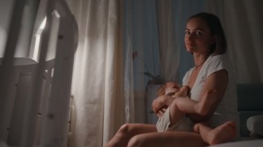Genç güzel annem, emzirme gece, onun yeni doğan bebek çocuk loş ışık. Anne emzirme bebek