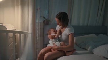 Genç güzel annem, emzirme gece, onun yeni doğan bebek çocuk loş ışık. Anne emzirme bebek