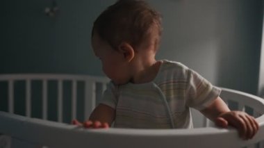 Genç anne ve bebek gece beşiğinde. Kadın çocuğa doğru eğildi, çocuk el kaldırdı.