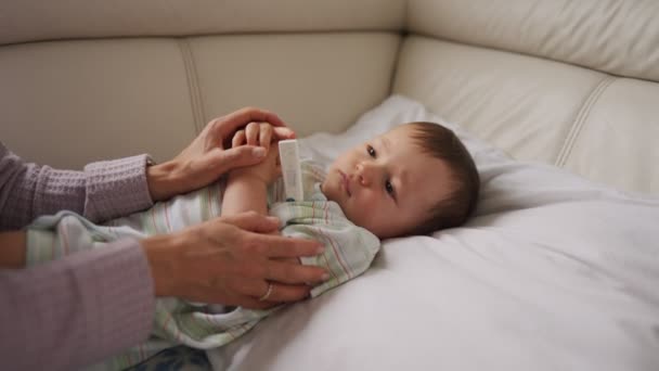 Meten van de temperatuur van haar moeder kind ziek op achtergrond. Ziek kind met hoge koorts, liggend op de Bank thuis. — Stockvideo