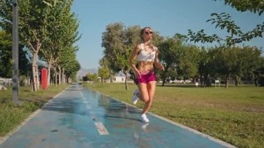 Genç bir kadın güneşli bir günde mavi bir yolda koşar. Adımları güçlü ve odaklanmış, ağır çekimde yakalanmış. Zindelik, özgürlük ve dayanıklılık kavramı. Geniş açılı dinamik açı doğal