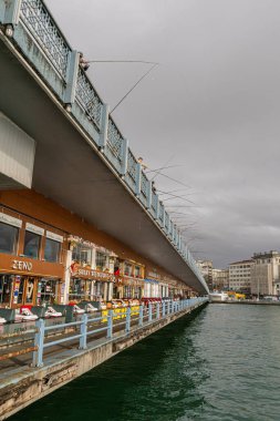 Yerel balıkçılar Galata Köprüsü boyunca kafe ve dükkanların üzerinde duruyorlar. İstanbul 'daki otantik günlük yaşam sahnesi, kültür, seyahat, kentsel yaşam tarzı ve kıyı gelenekleriyle ilgili hikayeler için ideal.
