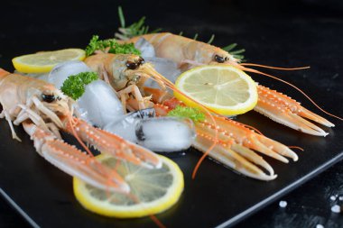 Buz ve Limonlu Kara Arkaplanda Çiğ Karidesler