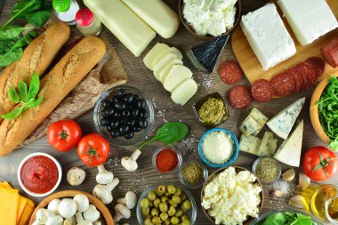 Tahta masadaki farklı peynir ve sebzeler.