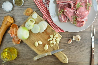 Baharatlı pirzola biftekleri ve ahşap masada otlar.