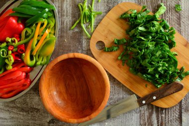 Arka planda taze sebzeler ve ahşap tahta var.