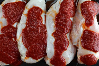 Siyah arka planda çiğ tavuk eti ve ketçap. en üstteki görünüm.