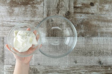 Ahşap bir masada kremalı bir kadın yemek hazırlıyor.