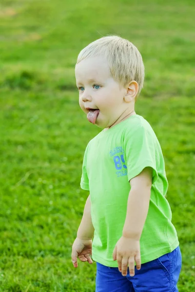 Портрет маленького блондина, показывающего язык, лето на свежем воздухе — стоковое фото