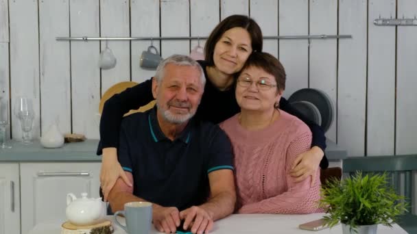 Oudere paar en volwassen dochter in de keuken glimlachend gelukkig en knuffelen, gelukkig gezin — Stockvideo