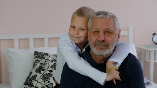 Glad gammal äldre farfar och liten sonson tittar på kameran och smilyng hemma — Stockvideo
