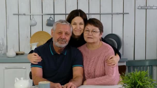 주방에서 미소짓고 있는 손 윗 부부와 성인 딸 은행 복하게 안아 주고 행복 한 가족을 위해 웃고 있다 — 비디오