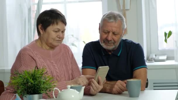 Yaşlı bir çift, olgun bir adam ve yaşlı bir kadın akıllı telefona bakıyor. — Stok video