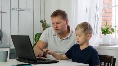 Oğlu olan babası bilgisayardan öğreniyor, evde uzaktan eğitim görüyor.