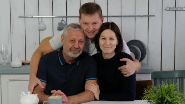 Senior gedragen man, volwassen zoon en dochter in de keuken glimlachen gelukkig en f knuffelen, gelukkig gezin — Stockvideo