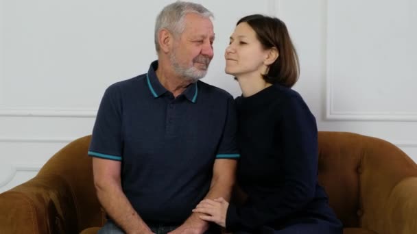 Portrét dospělého vousatého staršího muže objímajícího svou dospělou dceru, sedícího doma na pohovce — Stock video