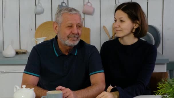 Oudere man en volwassen dochter in de keuken glimlachend vrolijk en knuffelend, gelukkig gezin — Stockvideo