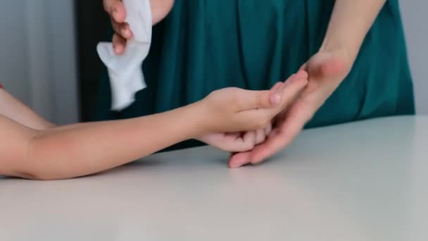 Женщина, использующая влажную антисептическую салфетку, чтобы очистить детские руки, защитить от вируса, пандемии, ковида. Закрыть — стоковое видео