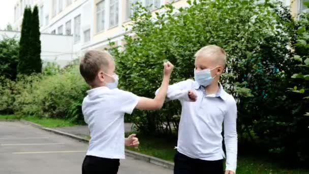 Nach der Quarantäne geht es zurück in die Schule. Niedliche Jungen Kinder grüßen kontaktlos und berühren ihre Ellbogen — Stockvideo