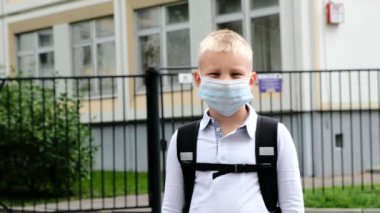 Okullu çocuk okulda kalıyor ve tıbbi maskeyi çıkarıyor. Okula geri dön..