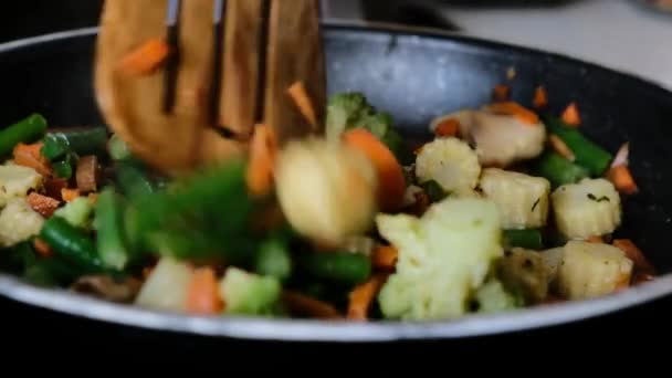 Close up view of colorful steaming vegetables frying on a pan being mixed and tossed up. — Stock video