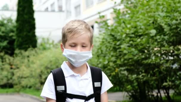 Liten pojke som går i skolan och bär medicinsk mask. Tillbaka till skolan. — Stockvideo