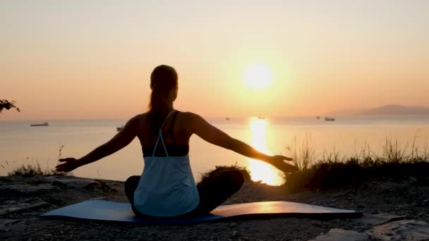 Tanınmayan bir kadın, deniz kıyısında meditasyon yapıyor. Gün batımı ışığı, Siluet. — Stok video