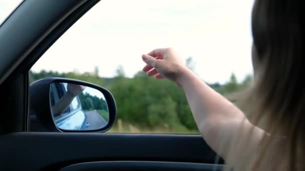 Vrouw reist met de auto vangt de wind met haar hand uit het autoraam. Zomer vrijheid concept — Stockvideo