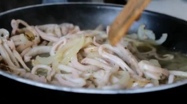 Kızartma tavasında baharatlı ve soğanlı kalamar halkaları. Kapat.