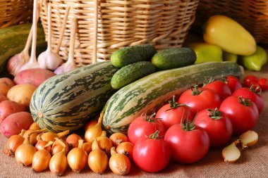 Hasır sepetleri arka planda masada farklı sebze vardır.