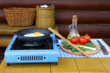 Terastaki gaz sobasında çırpılmış yumurta, ot ve domates pişiriyorum.. 