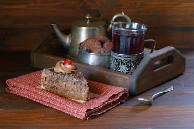 Çikolatalı kek, çay partisi için ahşap tepsinin önünde antika çatal bıçaklarla..