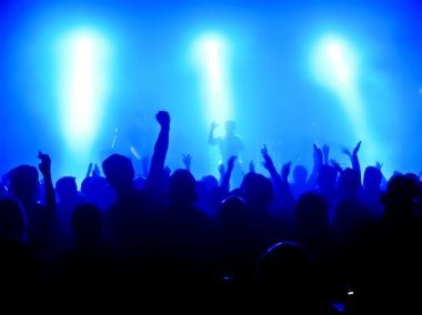 Parlak sahne ışıkları önünde konser kalabalığının siluetleri
