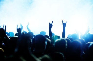 Parlak sahne ışıkları önünde konser kalabalığının siluetleri
