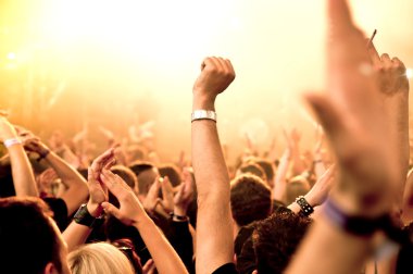 Parlak sahne ışıkları önünde konser kalabalığının siluetleri