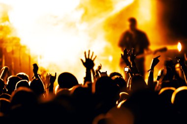 Parlak sahne ışıkları önünde konser kalabalığının siluetleri