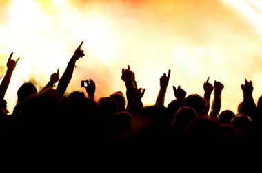 Parlak sahne ışıkları önünde konser kalabalığının siluetleri