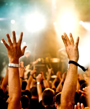 Parlak sahne ışıkları önünde konser kalabalığının siluetleri